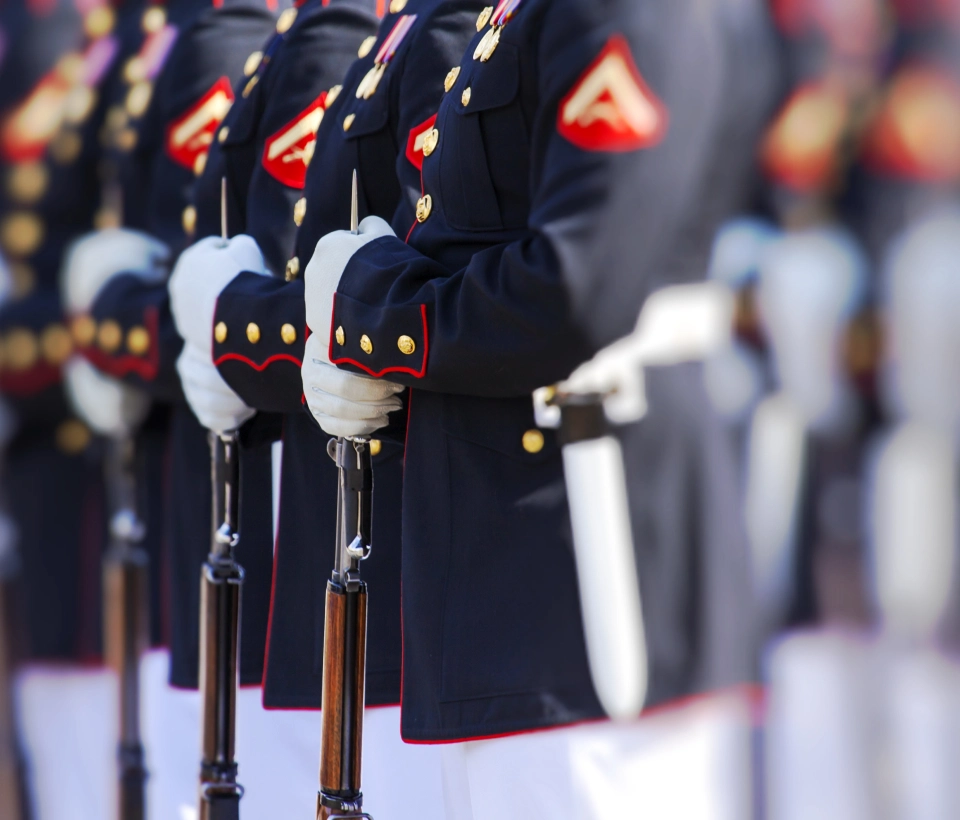 Marines in dress uniform holding rifles.