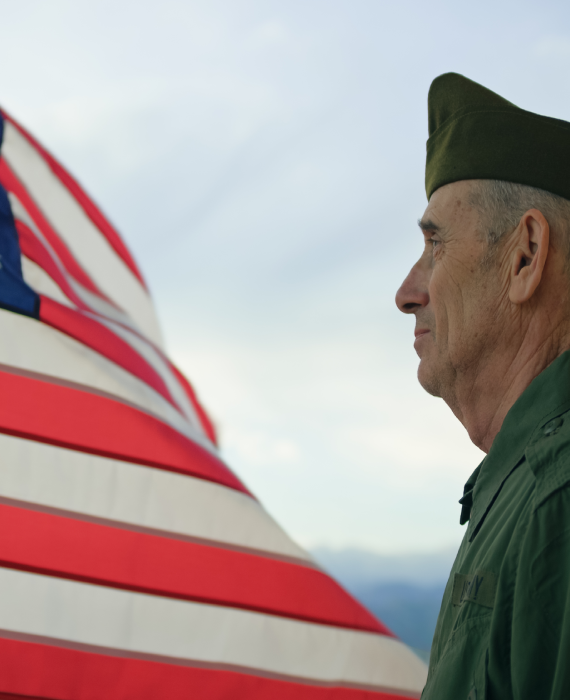 Here's an alt text option for the image: Veteran saluting American flag.