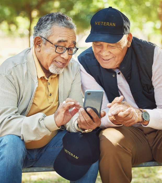 Two veterans looking at a smartphone.